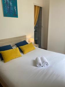 Un dormitorio con una cama blanca con almohadas amarillas y azules en La Villa B, en Cholet