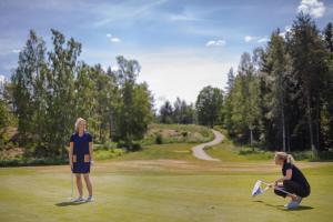 dos mujeres de pie en un campo de golf volando una cometa en Hotell Miskarp, en Mjölby