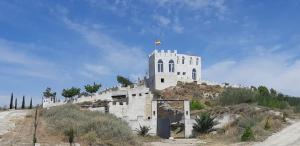Un edificio su una collina con una bandiera sopra di Hotel Cueva Tardienta Monegros-Adults Only a Tardienta