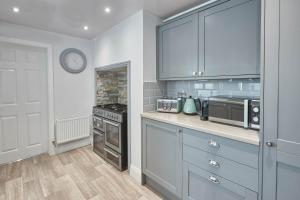 a kitchen with blue cabinets and a stove top oven at Host & Stay - Riftswood at Ruby in Saltburn-by-the-Sea +7 photos