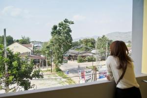 a woman standing on a ledge looking out of a window at U Dee Room and Coffee in Kanchanaburi City