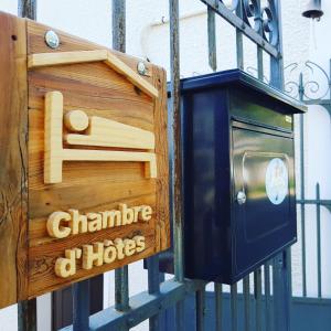 a wooden sign on a gate with a bird house at Le Panoramique in Auvers-sur-Oise