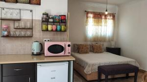 Ein kleines Zimmer mit einem Bett und einer Mikrowelle auf einer Theke in der Unterkunft Martini Dead Sea in Neve Zohar