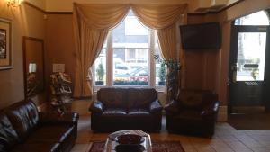 a living room with leather furniture and a large window at Hyde Park Court Hotel in London