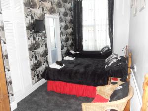 a bedroom with a black bed and a window at Bradleys Hotel in Blackpool