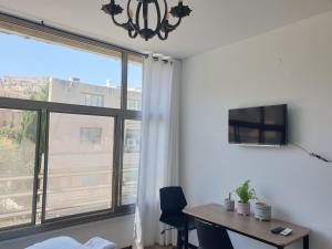 een kamer met een bureau en een groot raam bij City Center Rooms in Nazareth