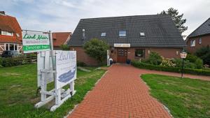 una casa con un cartel frente a una entrada de ladrillo en Hotel vom Land zum Meer en Jork