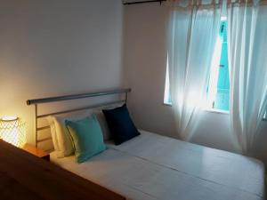 een slaapkamer met een bed met 2 kussens en een raam bij The Beach House - Historic Center - Duna Parque Group in Vila Nova de Milfontes
