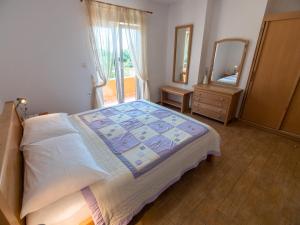 a bedroom with a large bed and a mirror at Apartmani Maslina in Tovrnele