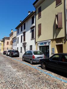 a cobblestone street with cars parked next to buildings at AKANTHO apartment in Mantova