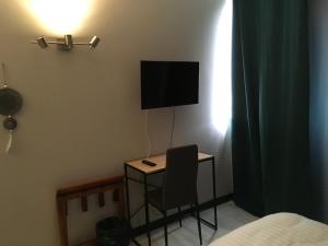 - une chambre avec un bureau, une chaise et une télévision dans l'établissement Hotel Dorele, à Montargis