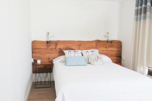 um quarto com uma cama branca e uma cabeceira em madeira em Casa Viges em El Pinar del Hierro