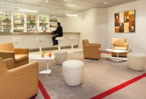 a man sitting at a bar in a waiting room at Mercure Paris Le Bourget Aeroport in Le Blanc-Mesnil