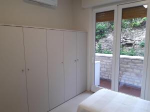 een witte slaapkamer met een bed en een raam bij Olivo House 2 in Portovenere
