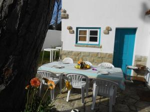 uma mesa com cadeiras brancas e uma porta azul em Casa Turquesa em Sintra