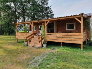 a large wooden cabin with a porch in the grass at Tiny House Het Reebokje in Vriescheloo