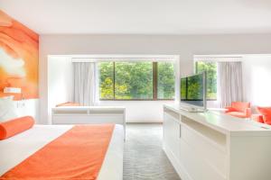 a bedroom with a bed and a desk with a television at Hotel Restaurant La Vague de Saint Paul in Saint Paul de Vence