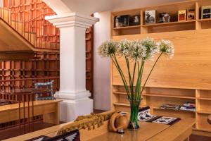 a vase with flowers on a table in a library at Hotel Ayook in Oaxaca City