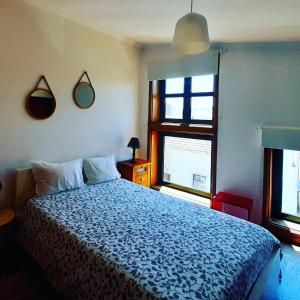 アヴェイロにあるAveiro center cozy Apartmentのベッドルーム1室(青い掛け布団、窓2つ付)