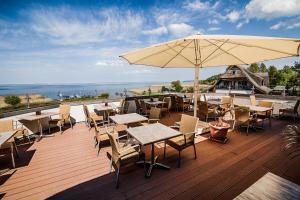 a deck with tables and chairs and an umbrella at HAFFHUS - Hotel & Spa in Ueckermünde