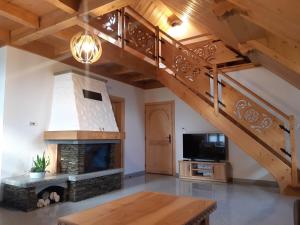 a living room with a staircase and a fireplace at Apartament Modrzewiowy Raj in Kluszkowce