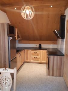 una cocina con armarios de madera y una lámpara de araña en Apartament Modrzewiowy Raj en Kluszkowce