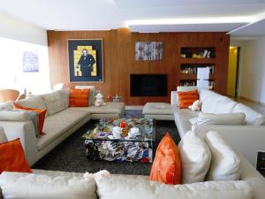 a living room with white couches and orange pillows at Hotel Restaurant La Vague de Saint Paul in Saint Paul de Vence