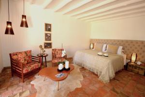 a bedroom with a bed and a chair and a table at Hotel Casa Terra in Villa de Leyva