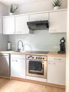 a kitchen with white cabinets and a stove top oven at Wohlfühl-Apartment Sinsheim, Nähe Therme und Museum in Sinsheim