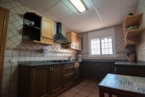 eine Küche mit Holzschränken, einer Spüle und einem Tisch in der Unterkunft Villa Javi in Riumar