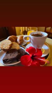 un piatto con pane e una tazza di caffè e un fiore di Hotel Suite Ares a Napoli
