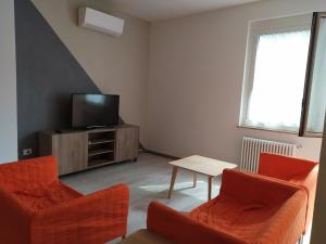 ein Wohnzimmer mit 2 orangenen Stühlen und einem TV in der Unterkunft IL DUOMO in Cesena