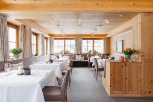 a restaurant with white tables and chairs and windows at Hotel Aurora in Lech am Arlberg
