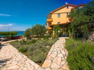 a house with a stone walkway next to a building at Apartmani Maslina in Tovrnele
