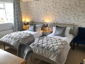 two beds in a hotel room with floral wallpaper at Ballifeary House in Inverness