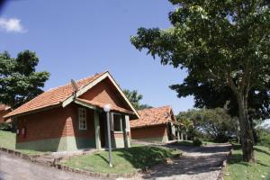 a house with a tree next to a street at Pousada Ecológica Rio do Peixe in Socorro