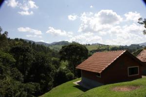 a small house on a hill with mountains in the background at Pousada Ecológica Rio do Peixe in Socorro