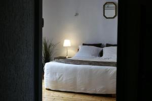a bedroom with a bed with white sheets and a lamp at Les Oiseaux de Passage in Saint-Gaultier