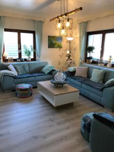 Sala de estar con sofás azules y mesa de centro en Haus Zissi, en Burg-Reuland