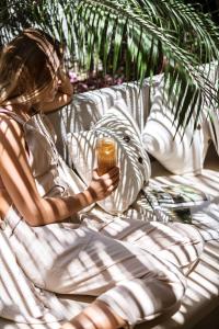 a woman sitting on a bed holding a drink at GAIA Alaçatı Bazaar in Alacati