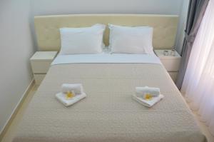 łóżko z dwoma białymi ręcznikami na górze w obiekcie Andaluni Beach Apartments w mieście Pržno