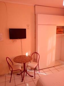 a table and two chairs and a television in a room at FICARE POA - 3min do Complexo Hospitalar Santa Casa in Porto Alegre
