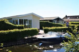 a boat in the water in front of a house at Resort Venetie Chalet nr.42 in Giethoorn