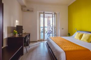 a bedroom with a bed and a desk and a balcony at Oasis in Acitrezza