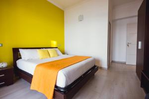 a bedroom with a large bed with a yellow wall at Oasis in Acitrezza