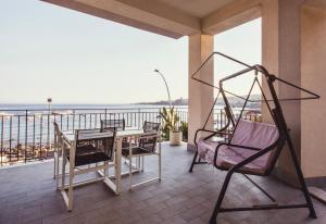 uma varanda com uma mesa e cadeiras e o oceano em Oasis em Acitrezza