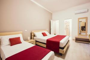 a bedroom with two beds with red and white sheets at Oasis in Acitrezza