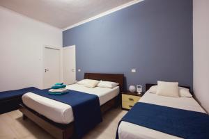two beds in a room with blue walls at Oasis in Acitrezza