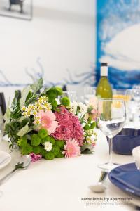 a table with a bouquet of flowers and a wine glass at Rovaniemi City Apartments in Rovaniemi
