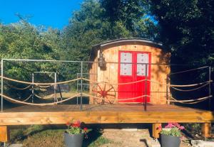 una pequeña casa con una puerta roja en una cubierta en La roulotte de Bussy en Bussières